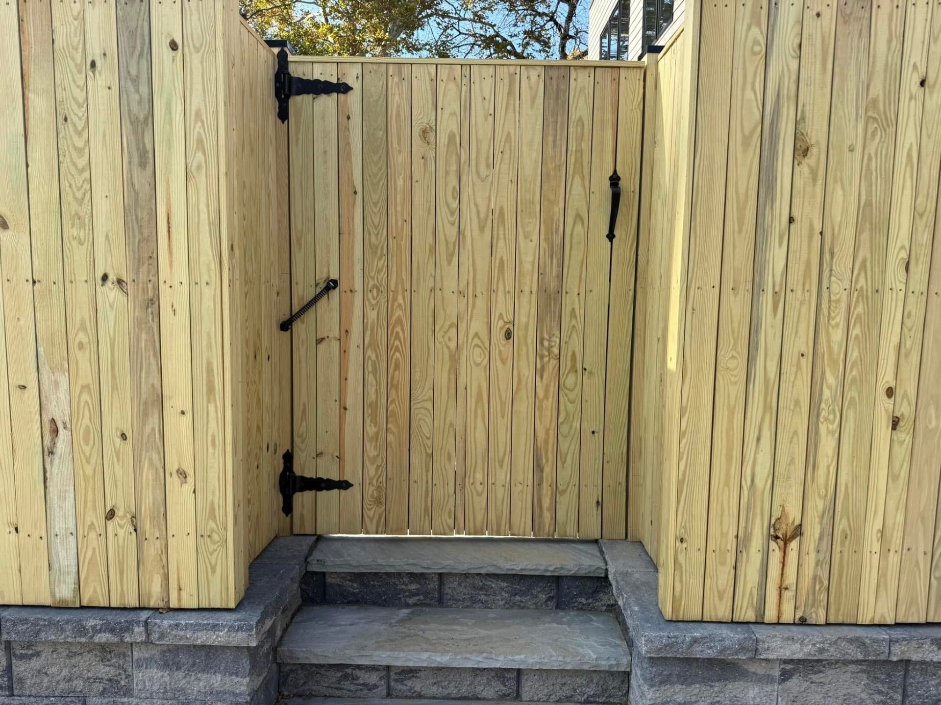 PT wood gate with black hardware on stone steps