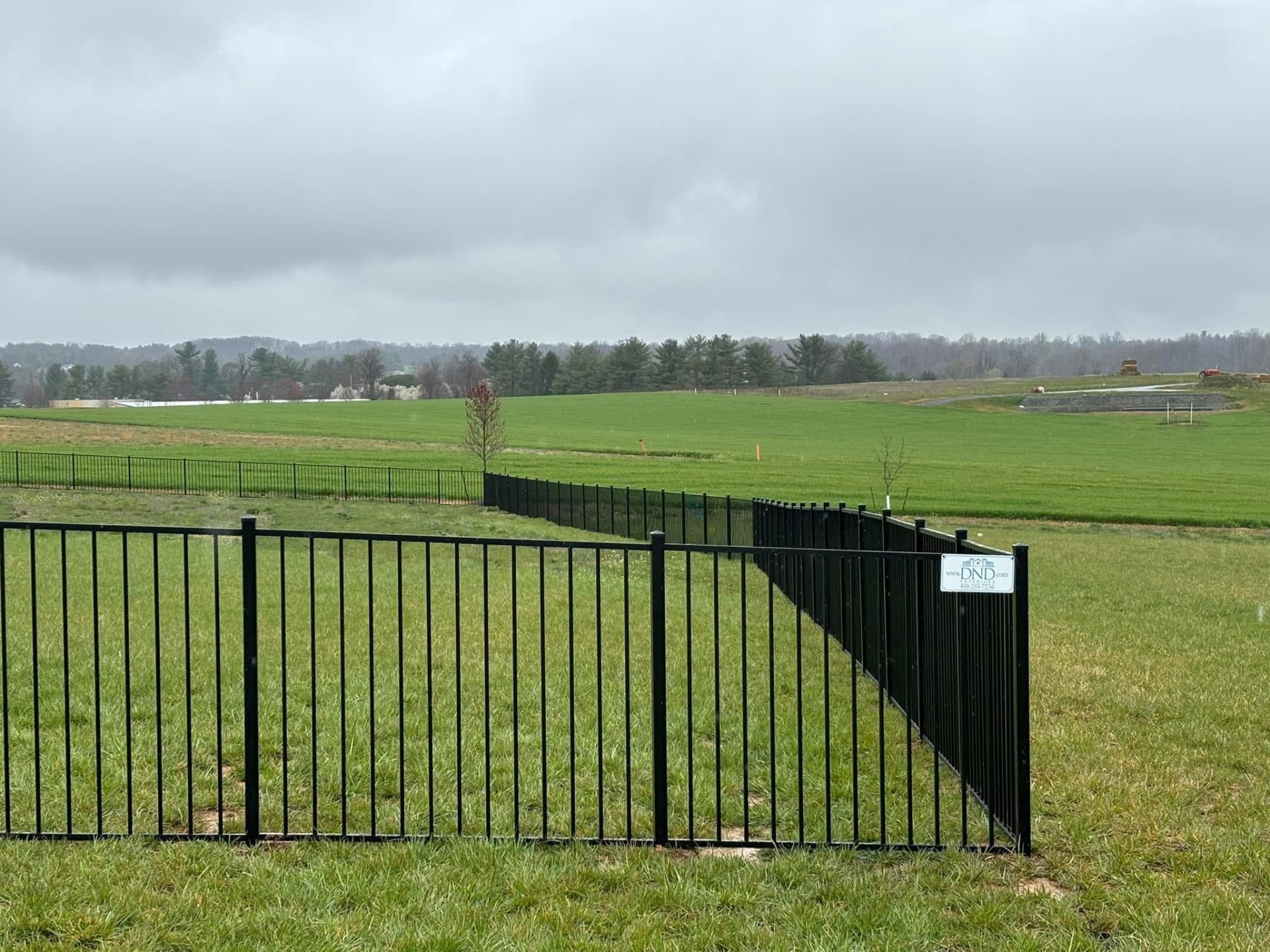 Black aluminum fence line across open field